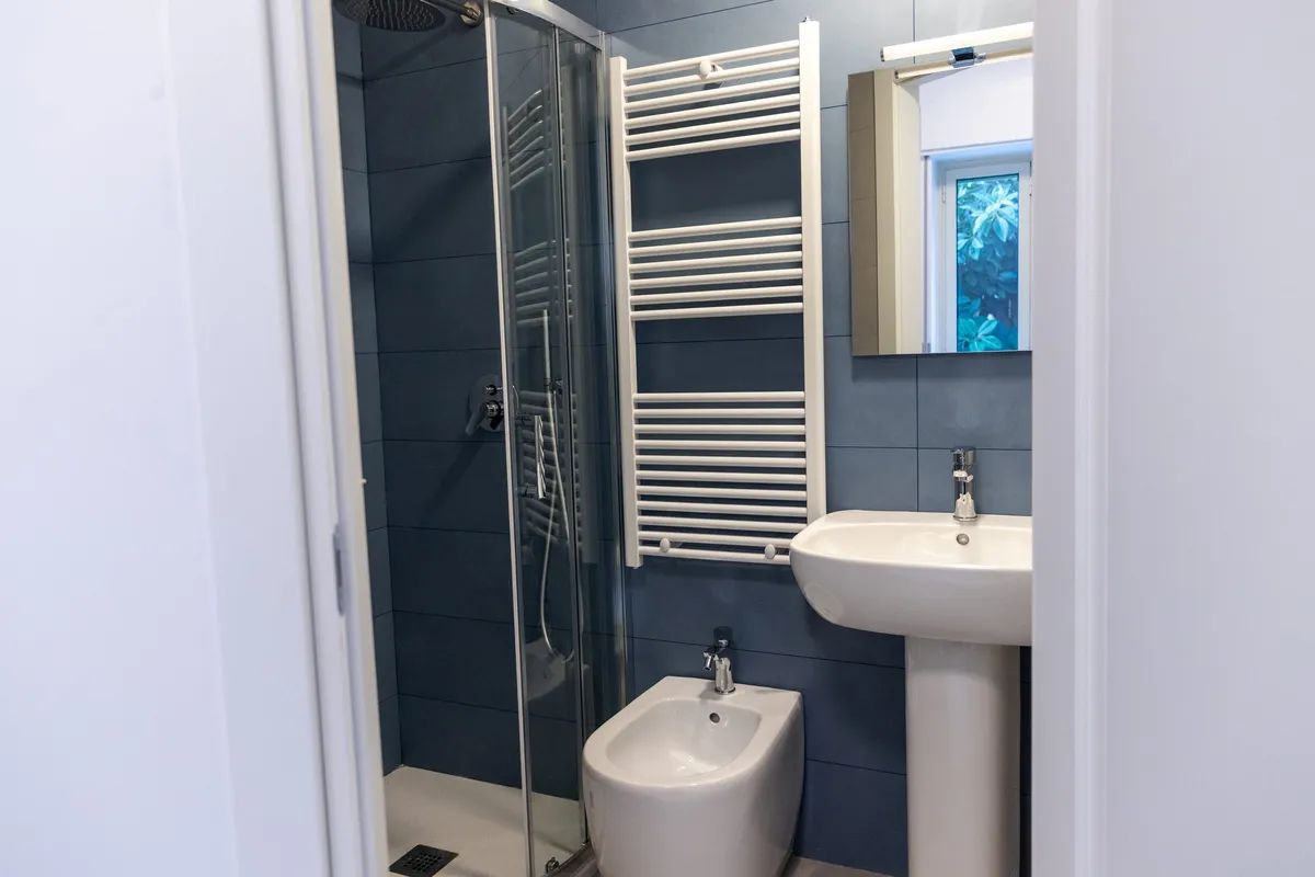 Baño privado con mampara de ducha, bidé, lavabo, espejo y toallero